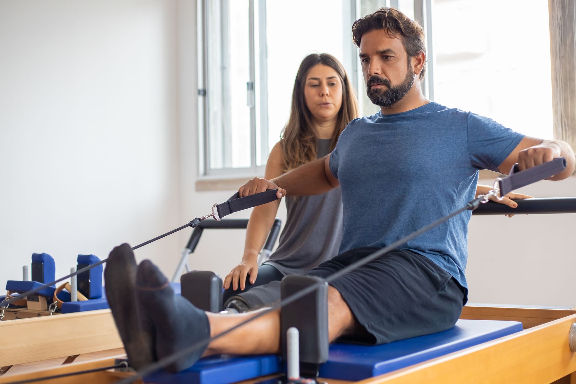 Profissional orientando um exercício de Pilates no aparelho — fotografia ilustrativa, não representa a clínica